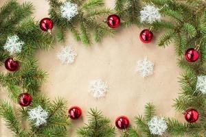 festliche weihnachtsgrenze mit roten kugeln auf tannenzweigen und schneeflocken auf rustikalem beige hintergrund foto