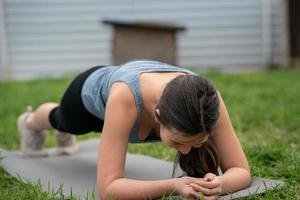 Fitness. Mädchen sitzt auf dem Rasen im Hof ihres Hauses und macht Verbrauchsteuern. foto