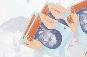 2 venezolanische Bolivar-Scheine liegen im Stapel auf dem Hintergrund einer großen halbtransparenten Banknote. abstrakte Darstellung der Landeswährung foto
