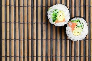 Sushi-Rollen liegen auf einer Nähmatte aus Bambusstroh. traditionelles asiatisches essen. Ansicht von oben. flacher Laienminimalismus mit Kopierraum foto