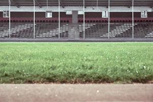 leere Zuschauerplätze im Stadion. im Vordergrund ist ein grünes Feld in Unschärfe. foto