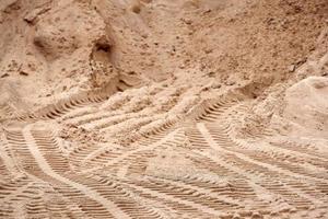 spuren von laufflächenbaugeräten auf dem sand. Hintergrund in Unschärfe. foto