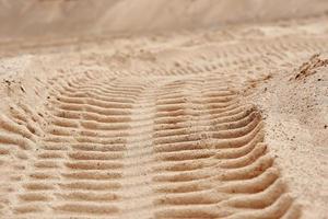 spuren von laufflächenbaugeräten auf dem sand. foto