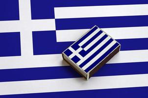 Die griechische Flagge ist auf einer Streichholzschachtel abgebildet, die auf einer großen Flagge liegt foto