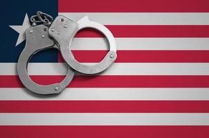Liberia-Flagge und Polizeihandschellen. das Konzept der Kriminalität und Straftaten im Land foto