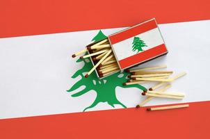 die libanonflagge ist auf einer offenen streichholzschachtel abgebildet, aus der mehrere streichhölzer fallen und auf einer großen fahne liegt foto