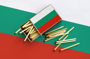 Die bulgarische Flagge wird auf einer offenen Streichholzschachtel gezeigt, aus der mehrere Streichhölzer fallen und auf einer großen Flagge liegt foto