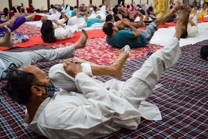 neu-delhi, indien, 19. juni 2022 - gruppen-yoga-übungssitzung für menschen verschiedener altersgruppen im balaji-tempel, vivek vihar, internationaler yoga-tag, große gruppe von erwachsenen, die an yoga-kursen im tempel teilnehmen foto