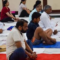 neu-delhi, indien, 19. juni 2022 - gruppen-yoga-übungssitzung für menschen verschiedener altersgruppen im balaji-tempel, vivek vihar, internationaler yoga-tag, große gruppe von erwachsenen, die an yoga-kursen im tempel teilnehmen foto