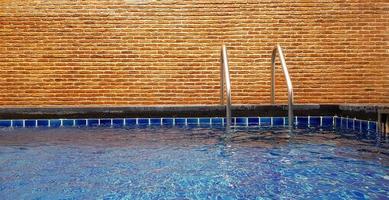 Swimmingpool mit Treppen- und Backsteinmauerhintergrund mit Kopienraum. Innenarchitektur und Struktur.