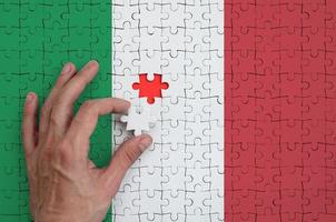 Die italienische Flagge ist auf einem Puzzle abgebildet, das die Hand des Mannes zum Falten vervollständigt foto