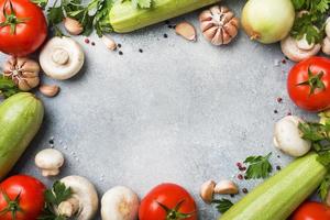 Set aus verschiedenen Gemüsesorten der Saison auf grauem Betonhintergrund. tomate zucchini zwiebel knoblauch champignons petersilie gewürze. Frame kopieren. foto