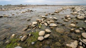 eine Nahaufnahme von schönen großen und kleinen nassen Steinen in einem See in einer ländlichen Gegend foto