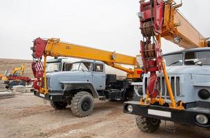 eine Reihe großer LKW-Kräne und Maschinen auf einer Industriebaustelle foto