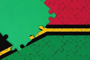 Die Vanuatu-Flagge ist auf einem fertigen Puzzle mit freiem Platz für grüne Kopien auf der linken Seite abgebildet foto