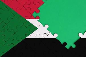 Die Sudan-Flagge ist auf einem fertigen Puzzle mit freiem Platz für grüne Kopien auf der rechten Seite abgebildet foto