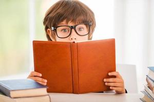 erstaunliche Geschichte überraschte den kleinen Jungen, der ein Buch las, während er am Tisch saß foto