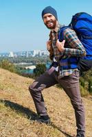 vorwärts und nur vorwärts hübscher junger mann, der rucksack trägt und mit einem lächeln in die kamera schaut foto