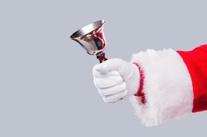 Jingle Bells Nahaufnahme des Weihnachtsmanns mit Metallglocke in der Hand und vor grauem Hintergrund foto