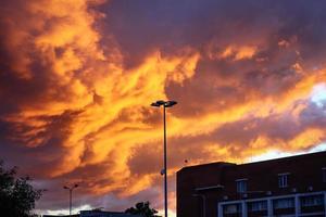 dramatische sonnenuntergangswolken im himmel über stadtgebäuden und hoher straßenlaterne mit videokamera foto