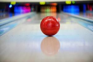 es wird eine Streik-Nahaufnahme der leuchtend roten Bowlingkugel sein, die entlang der Bowlingbahn rollt foto