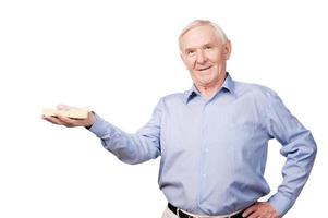 reicher Senior. selbstbewusster älterer Mann im Hemd mit Geld und Blick in die Kamera, während er vor weißem Hintergrund steht foto