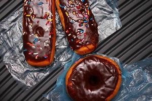 Schokoladen-Donuts und Schoko-Donut-Riegel mit mehrfarbigen Zuckerflocken. platziert auf einem grauen Aluminiumboden. foto