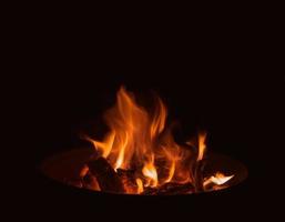 eine Flamme, die im Dunkeln in einem Kohlenbecken brennt foto