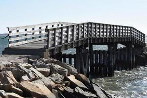 Abgenutzte Holzfußbrücke über den Ozean foto