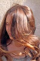 Mädchen mit langen Haaren, die sich im Wind in den Sonnenstrahlen entwickeln, Nahaufnahmeporträt foto