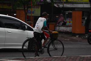 magelang, indonesien, 2022 - Foto eines alten Mannes, der am Nachmittag mit dem Fahrrad am Straßenrand fährt