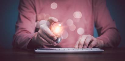 Hand berührt Glühbirne, leuchtende Glühbirne und SMS auf der Tastatur, neue Idee mit Innovation und Inspiration, innovative Technologie in Wissenschaft und Kommunikationskonzept. foto