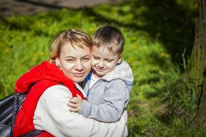 Kinder mit ihrer Mutter posieren auf einer sonnigen Lichtung in der Nähe eines Baumes im Wald. die Sonnenstrahlen umhüllen den Raum. Interaktionsgeschichte. Platz zum Kopieren. foto