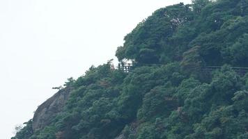 Die wunderschönen Berglandschaften mit dem grünen Wald und einer Plankenstraße, die entlang einer Klippe in der Landschaft Chinas gebaut wurde foto