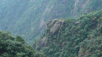 Die wunderschönen Berglandschaften mit dem grünen Wald und einer Plankenstraße, die entlang einer Klippe in der Landschaft Chinas gebaut wurde foto