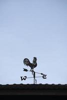 Die alte Windfahne mit einem Hahnsymbol auf dem Dach, traditionelle Technologieausrüstung zur Vorhersage und Messung des Windwetters in der Luft, Vintage-Dekoration, Windrichtungsinstrument. foto