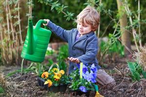 kleiner Junge, der im Garten arbeitet und Blumen pflanzt