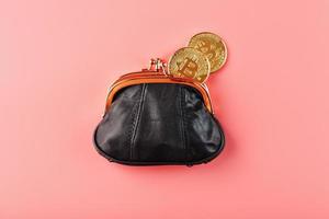 klassische schwarze Brieftasche mit Bitcoin-Münzen auf rosafarbenem Hintergrund. foto