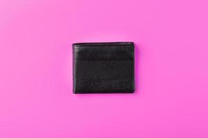 schwarze Geldbörse auf rosa Hintergrund. Symbol für Wohlstand und Wohlstand. foto