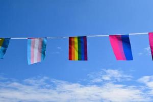 lgbtq-flaggen wurden an einem sonnigen tag an draht gegen den blauen himmel gehängt, weicher und selektiver fokus, konzept für lgbtq-genderfeiern im stolzmonat auf der ganzen welt. foto