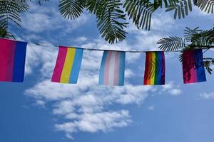 lgbtq-flaggen wurden an einem sonnigen tag an draht gegen den blauen himmel gehängt, weicher und selektiver fokus, konzept für lgbtq-genderfeiern im stolzmonat auf der ganzen welt. foto