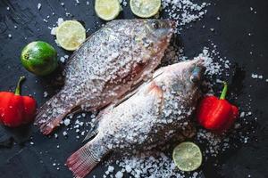 frische Tilapia-Fische mit Salz und Gewürzen foto