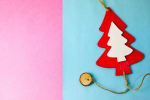 festliches weihnachten des neuen jahres schöner heller bunter fröhlicher blauer und rosa hintergrund mit einem kleinen spielzeug aus holz rot-weißem süßem weihnachtsbaum. flach liegen. Ansicht von oben. Feiertagsdekorationen foto