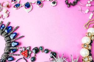 Wunderschöner, kostbarer, glänzender Schmuck, trendiges, glamouröses Schmuckset, Halskette, Ohrringe, Ringe, Ketten, Broschen mit Perlen und Diamanten auf rosafarbenem Hintergrund. flache Lage, Draufsicht, Kopierplatz foto