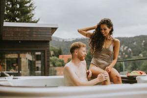 junges Paar, das im Urlaub im Whirlpool im Freien genießt foto