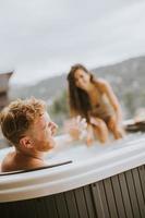 junges Paar, das im Urlaub im Whirlpool im Freien genießt foto