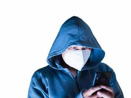 asiatischer mann in hoodie und maske, der etwas vom handy auf weißem hintergrund mit beschneidungspfad hackt foto