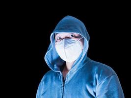 asiatischer Mann in Hoodie und Maske mit großen Augen, die ein gruseliges Gesicht auf schwarzem Hintergrund bedrohen, Beschneidungspfad foto