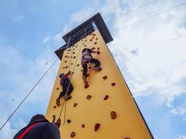 Zwei Jugendliche steigen den gelben Outdoor-Kletterturm hinauf foto