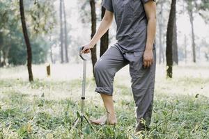 junge asiatische physiotherapeutin, die mit einer älteren frau beim gehen mit einer gehhilfe arbeitet foto